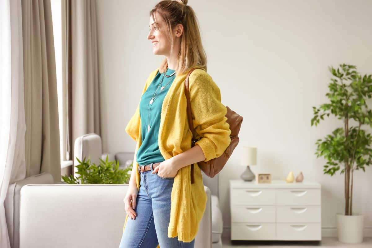 Femme souriante portant un cardigan jaune et un sac à dos