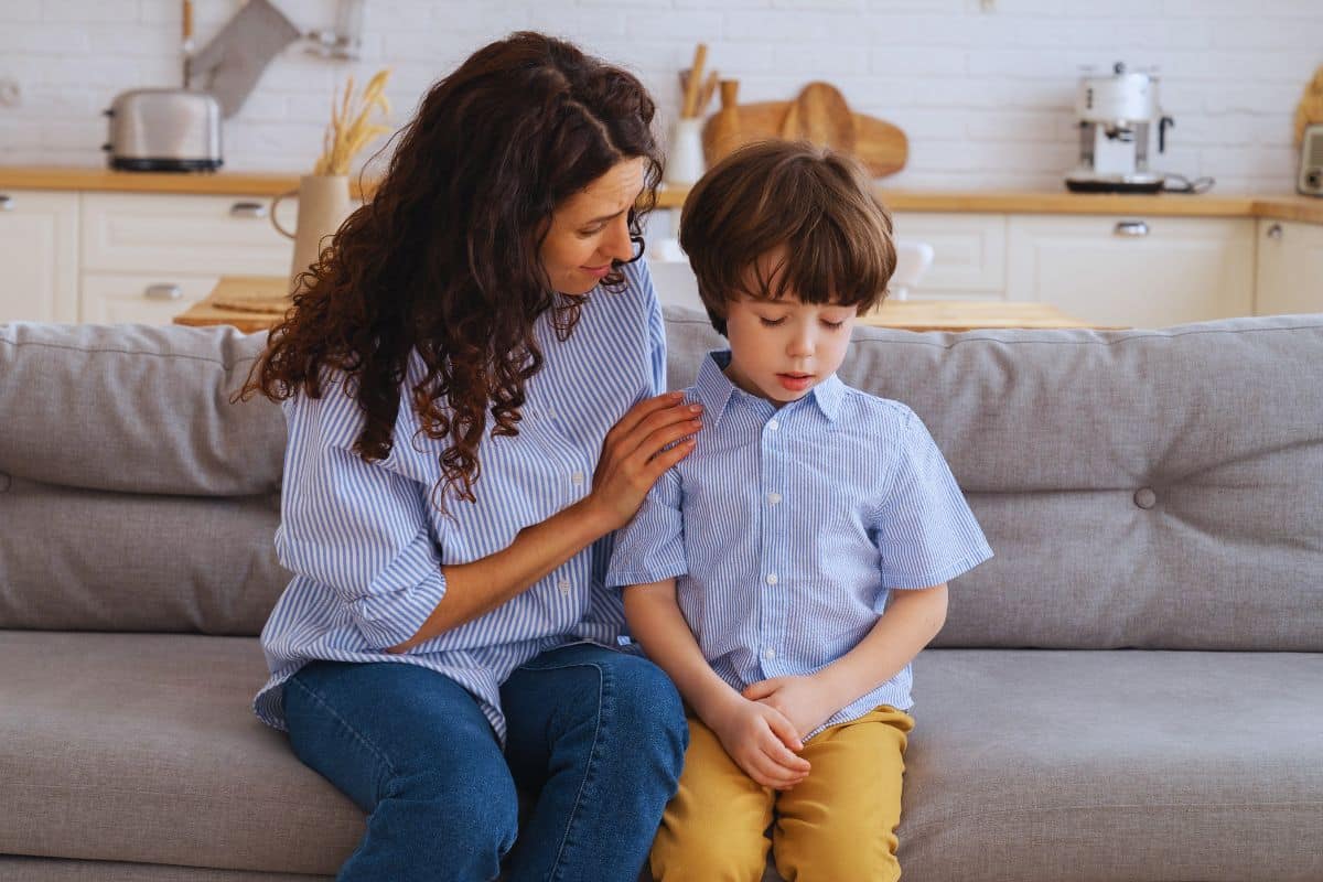 Une mère réconforte son fils en lui parlant sur le canapé.