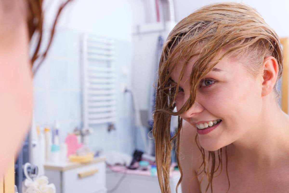 Femme mouillant ses cheveux avant de plonger dans une piscine.