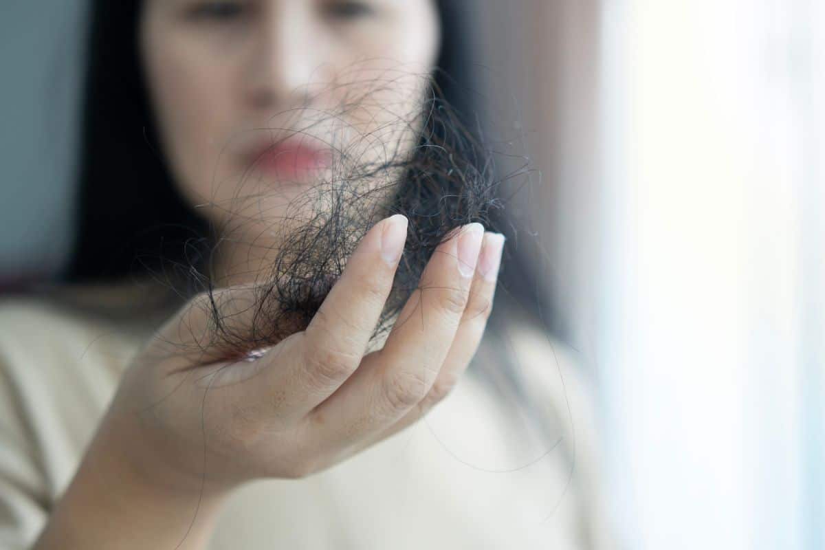 Femme tenant une poignée de cheveux tombés.
