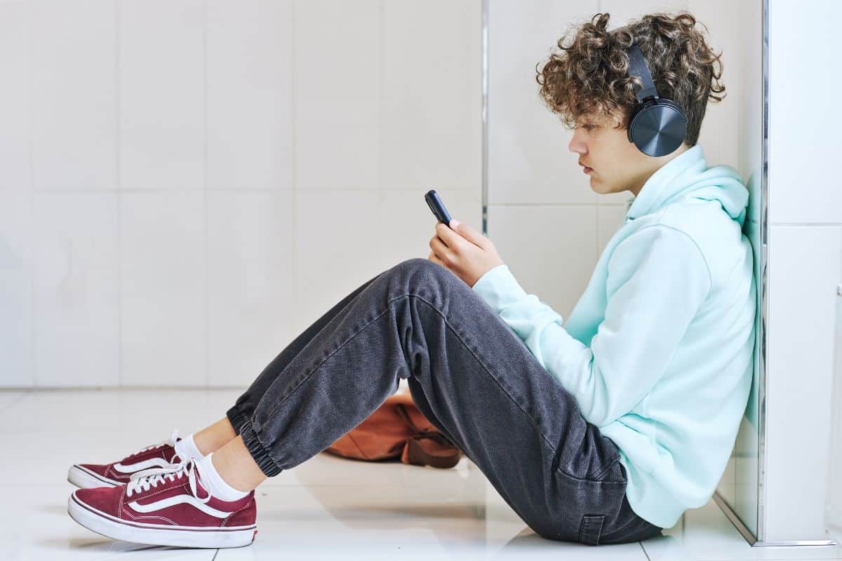 Jeune homme assis au sol écoutant de la musique avec un casque.
