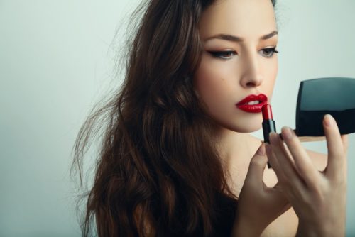 Femme qui met du rouge à lèvres