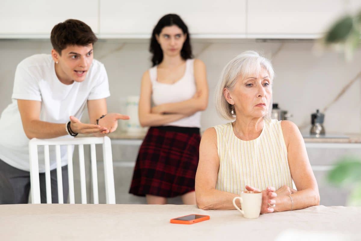 Un homme essaie de discuter avec sa mère tandis que sa compagne observe avec frustration.