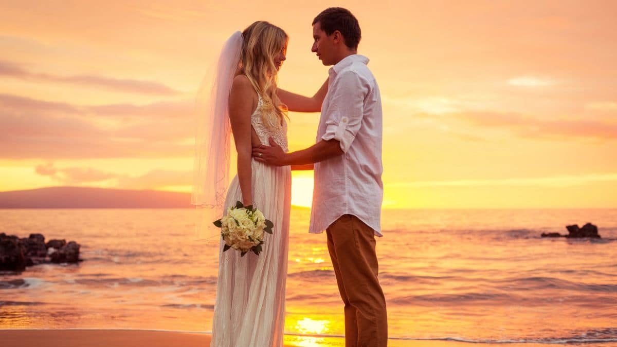 Couple de mariés sur une plage au coucher du soleil à Hawaï.