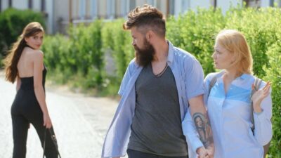 Un homme en couple regarde une autre femme qui passe, créant une tension.
