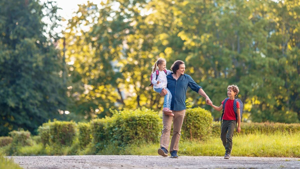 Un père marchant avec ses deux enfants souriants