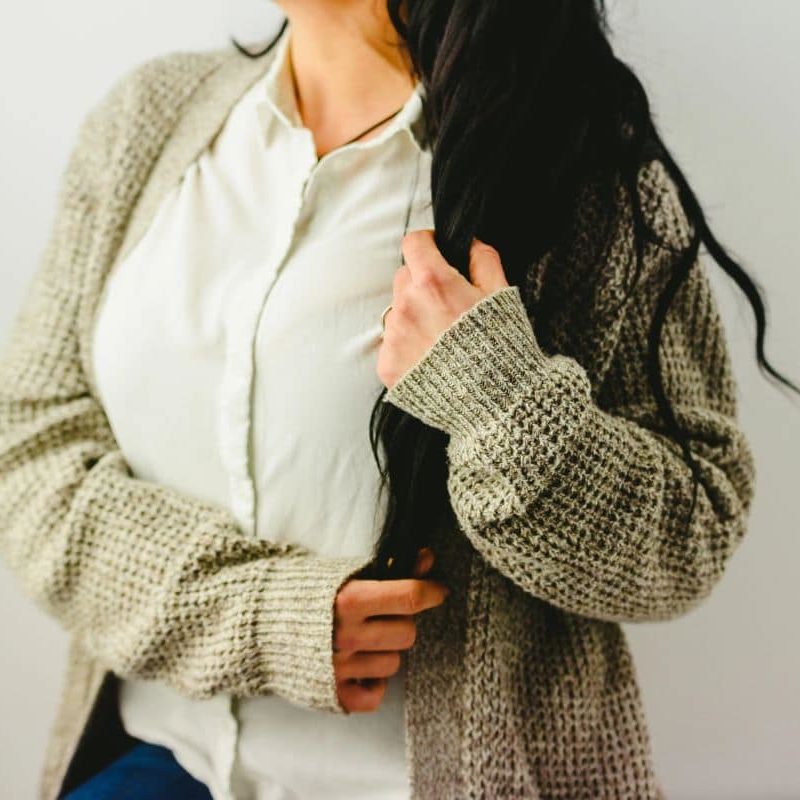 Femme portant un cardigan gris en superposition avec une chemise blanche.
