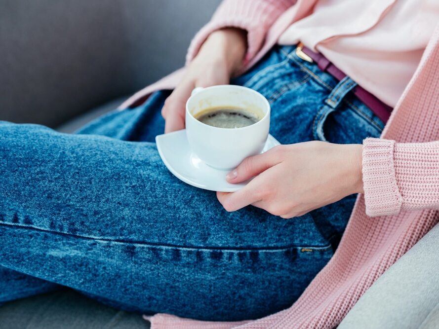 Femme en jean qui boit un café