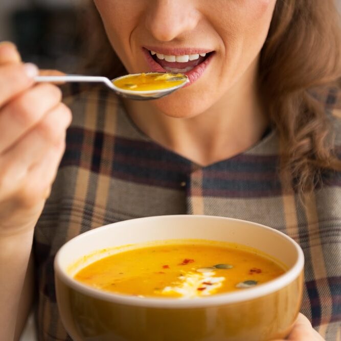 Jeune femme mangeant de la soupe