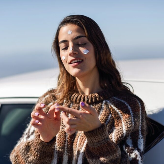 Femme qui met de la crème solaire en hiver