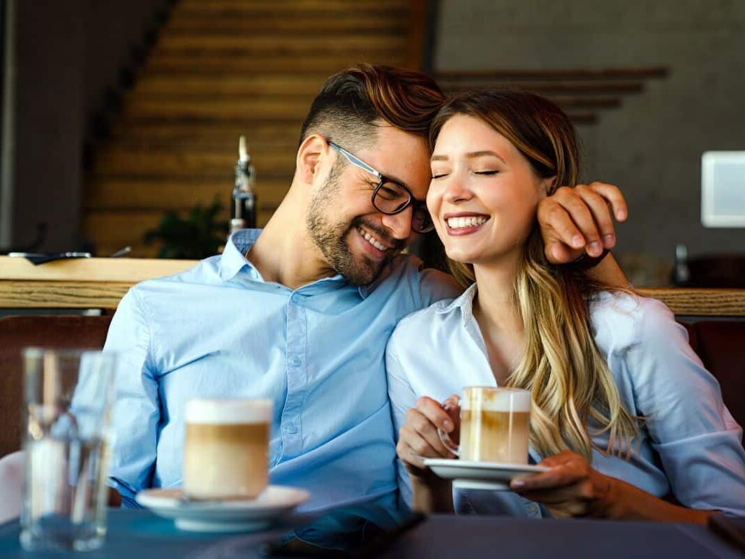 Un couple heureux partage un moment complice dans un café.